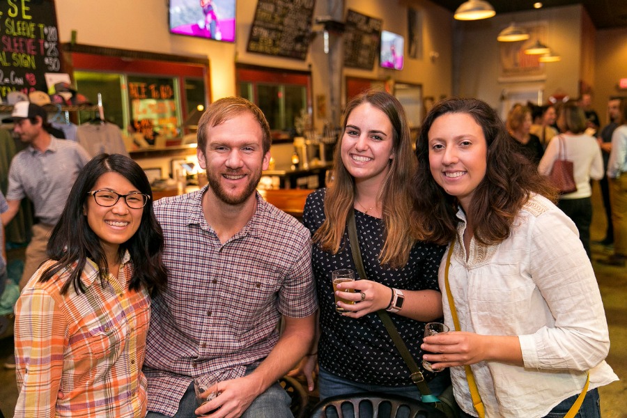Three women and a man stand in front of a bar, smiling and looking at the camera during a Holland Lifelong Learning event thrown by the South Carolina Aquarium.